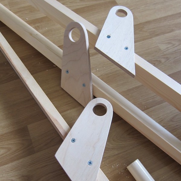 Some wooden components which are parts of a coat and shoe rack under construction lying on a laminate wood floor.