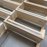 Pale wooden IKEA spice racks lying on a grey tile floor in an interleaved arrangement